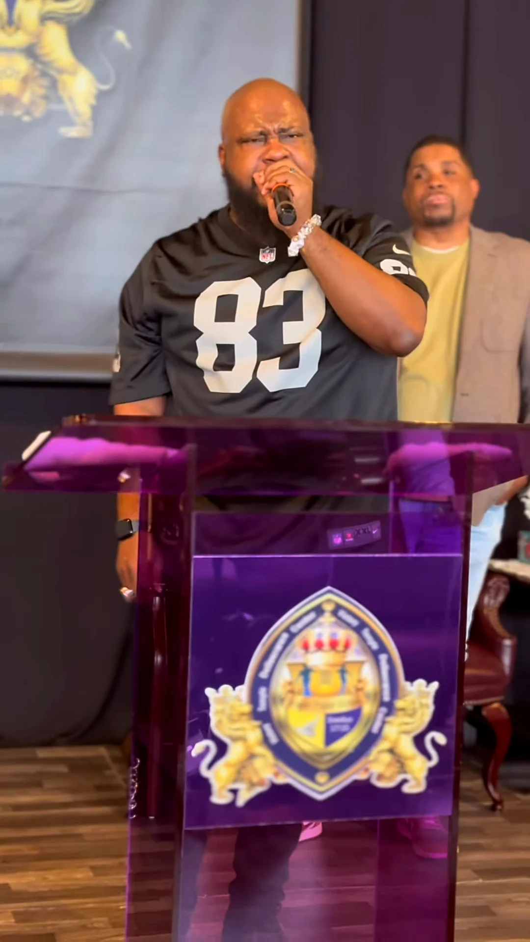 A praise leader in a number 83 football jersey sings at the purple VTDC pulpit on Kickoff Sunday